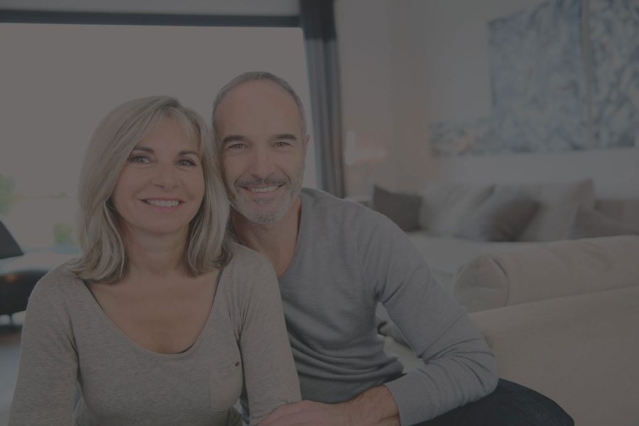 Couple smiling together in a cozy living room, representing home buying and family life, relevant to mortgage and loan services.
