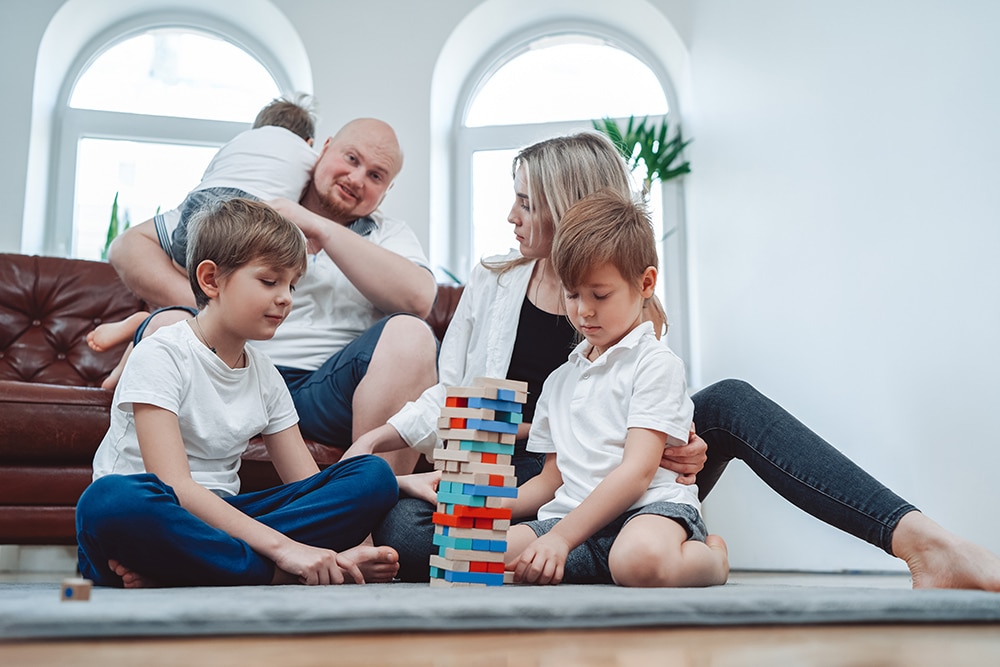 Cheerful family playing Jenga together in a bright living room, emphasizing family bonding and fun activities at home, relevant to USDA loan benefits for first-time buyers.