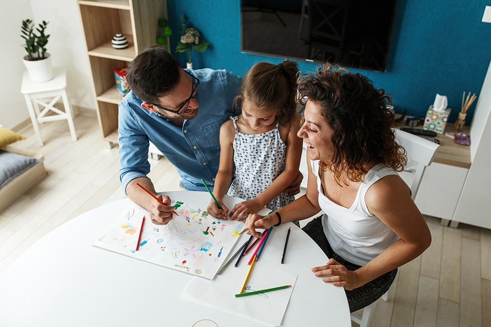 Family enjoying quality time at home, coloring together with crayons on a table, reflecting the importance of family engagement in a cozy living space.