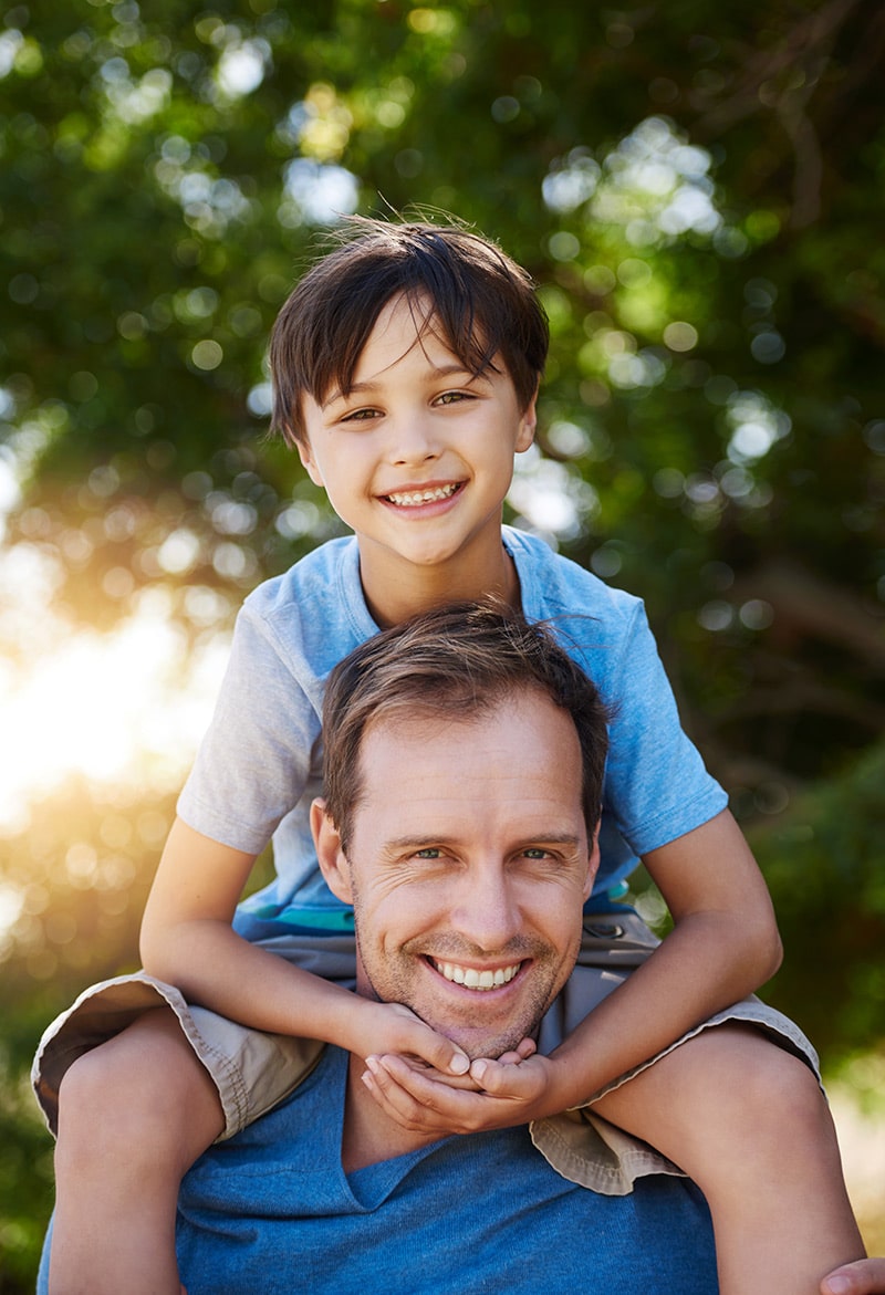 Father and son smiling together outdoors, showcasing family bonds and joy, relevant to homebuyer support and mortgage process guidance.