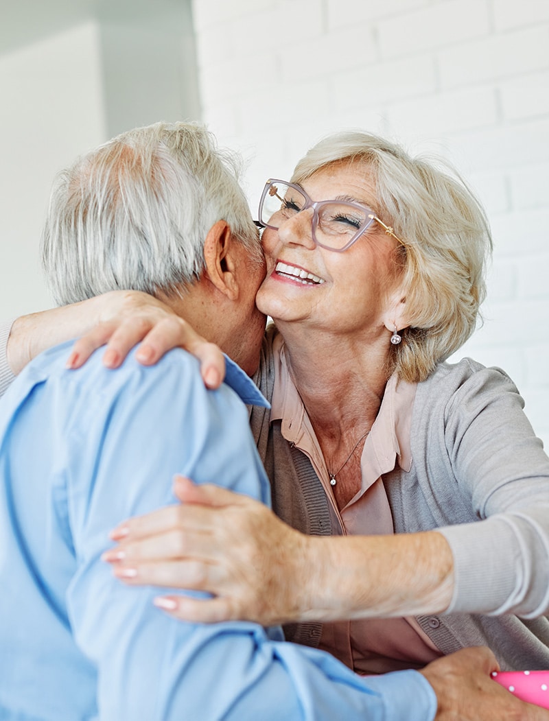 Senior couple embracing at home, symbolizing emotional connection and financial stability in retirement, relevant to reverse mortgage benefits.