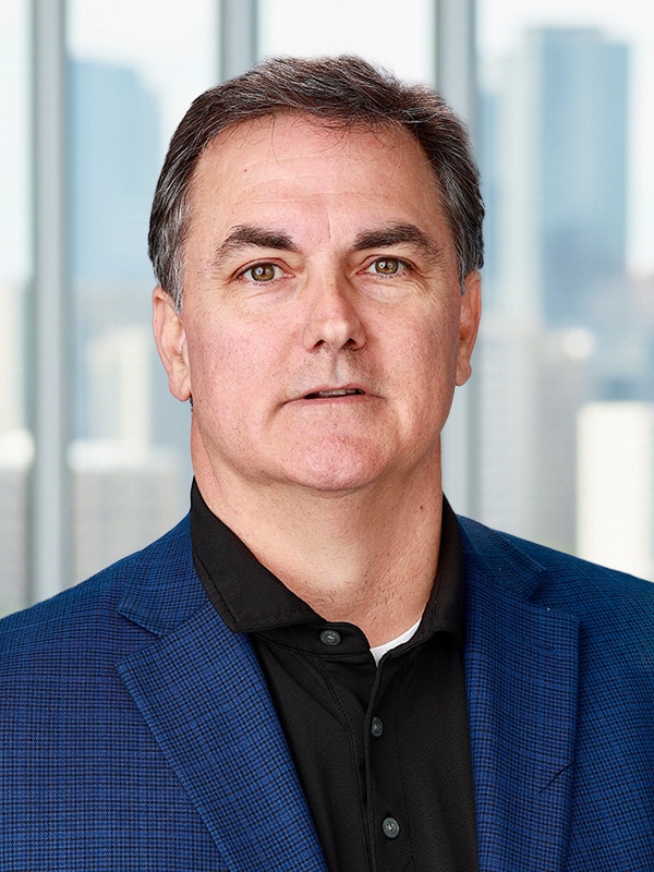 Joe O'Connor, Operations Manager and Mortgage Loan Originator at Loan Velocity, Inc., in a professional blue blazer, with a city skyline background, representing expertise in mortgage solutions.